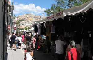 Markeder. Billedet viser et italiensk marked, hvor man kan se de små boder og italienere, der går rundt.