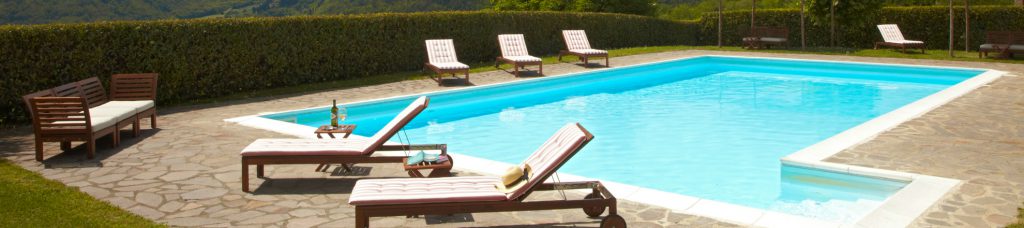 Billedet viser et Colognole livsnyderophold. Billedet indeholder en lækker blå swimmingpool, der er omringet af flotte liggestole med hynder.